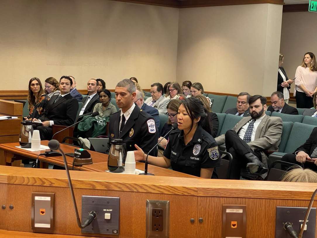 Selena, in EMS uniform, testifying at a government hearing